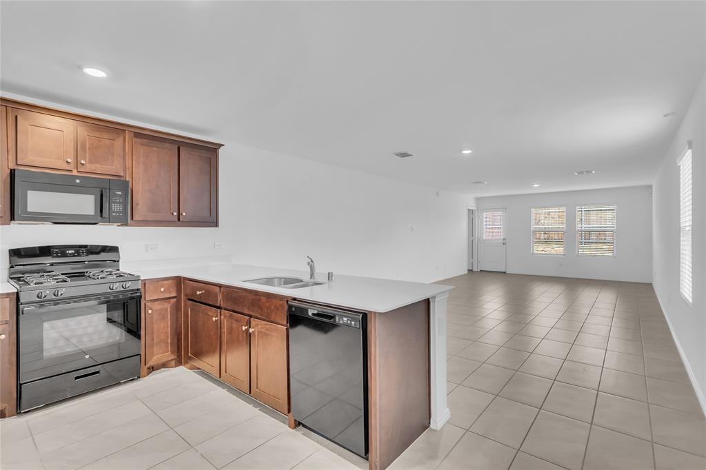 14069 Drover Street Pilot Point, TX 76258 - Photo 3 of 27 a kitchen with stainless steel appliances granite countertop a stove a sink and a microwave