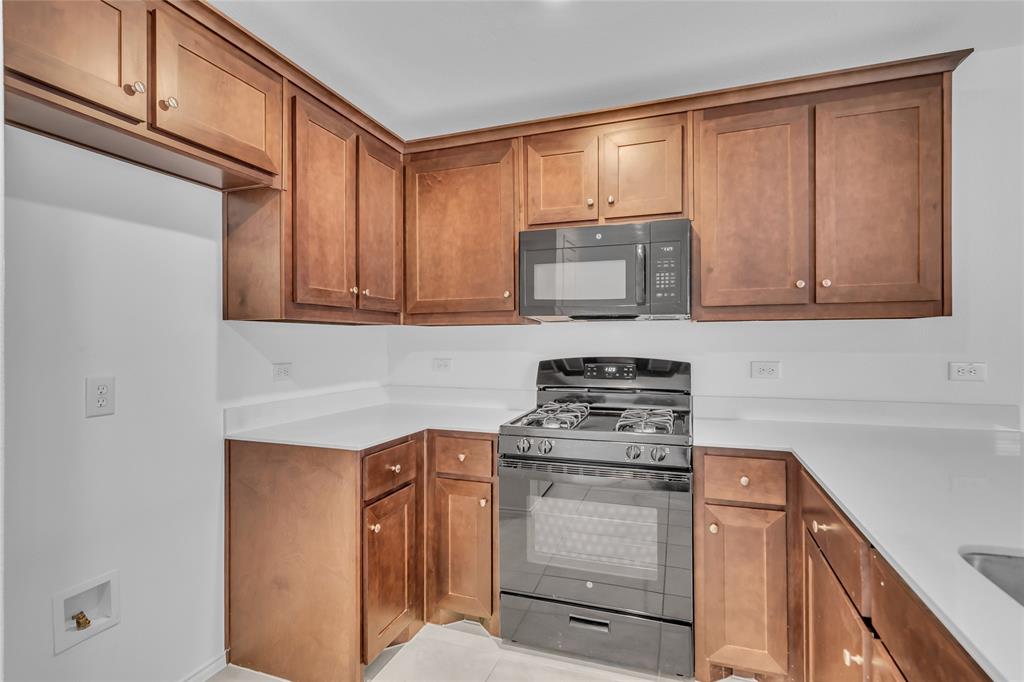 14069 Drover Street Pilot Point, TX 76258 - Photo 5 of 27 a kitchen with stainless steel appliances granite countertop a sink stove and microwave