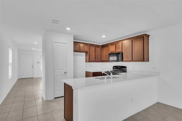 a kitchen with stainless steel appliances a sink a stove a refrigerator cabinets and a window