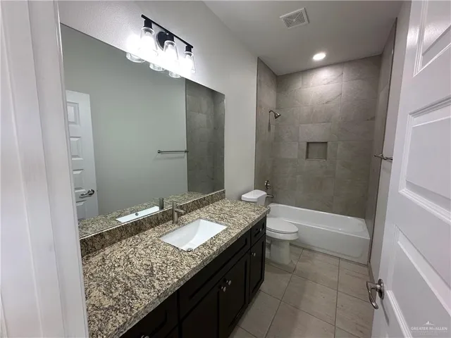 a bathroom with a granite countertop sink a toilet and shower
