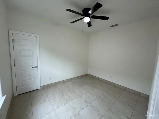 an empty room with a ceiling fan and carpet