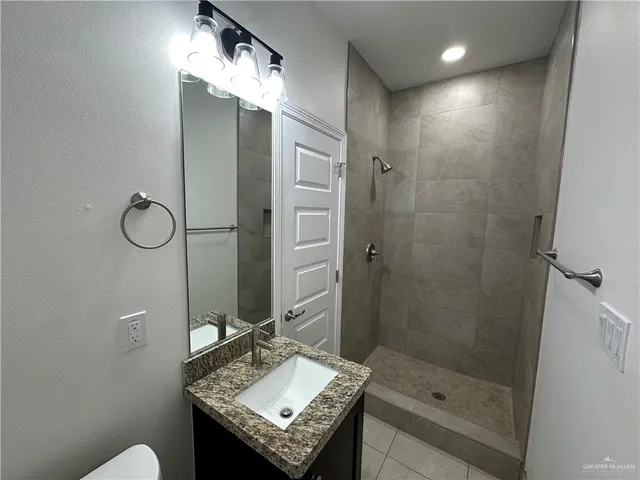 a bathroom with a shower sink vanity and mirror