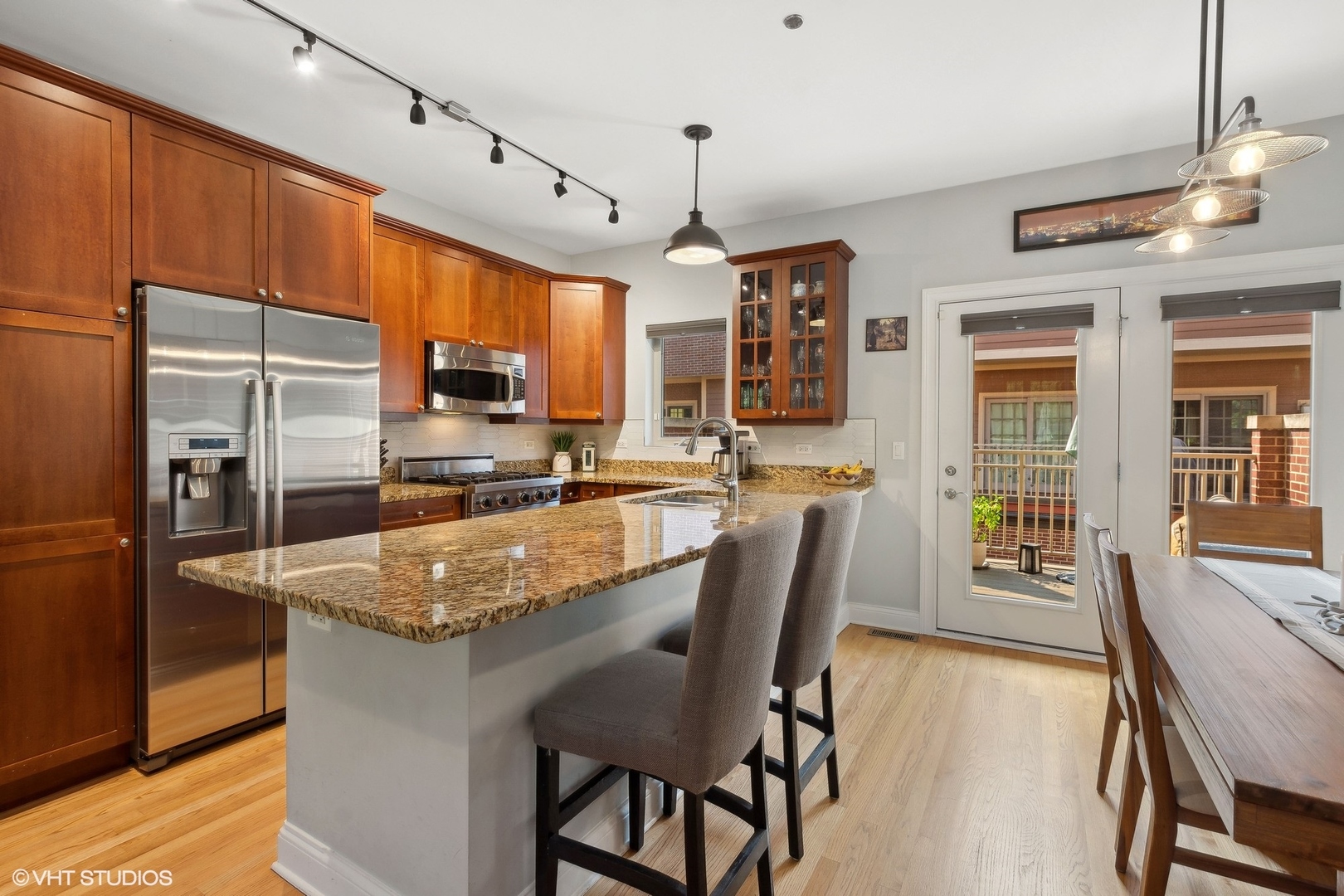 3003 West Cornelia Avenue Chicago, IL 60618 - Photo 4 of 25 a kitchen with stainless steel appliances granite countertop a table chairs refrigerator and microwave