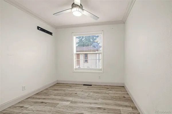 an empty room with wooden floor fan and windows