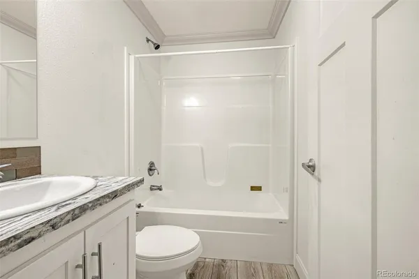 a bathroom with a granite countertop bathtub shower sink vanity and toilet