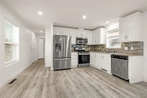 a kitchen with kitchen island a refrigerator a stove a sink and white cabinets
