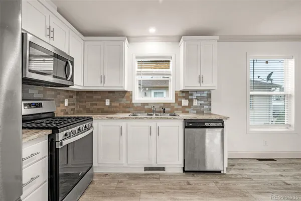a kitchen with stainless steel appliances granite countertop a stove a sink and a microwave