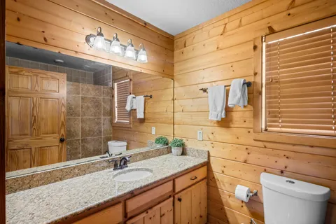a bathroom with a granite countertop sink a toilet and mirror
