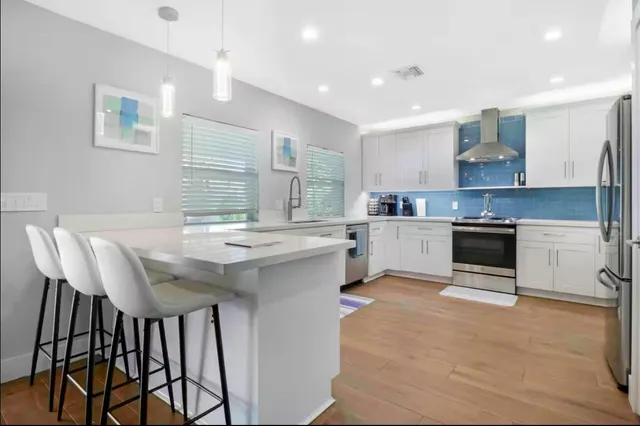 a kitchen with kitchen island a stove a table and chairs in it