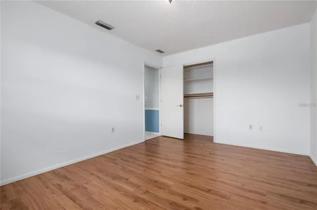 a view of an empty room with wooden floor and closet