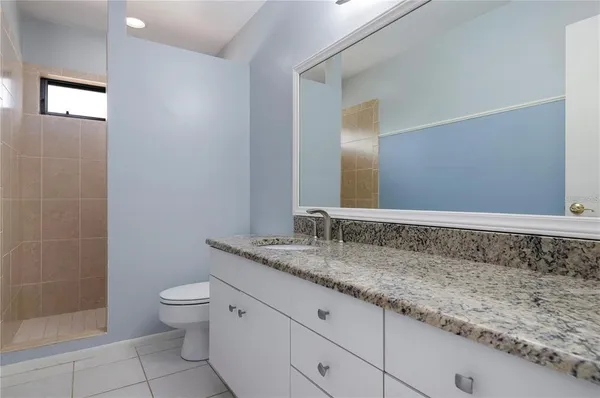a bathroom with a granite countertop sink a toilet and mirror