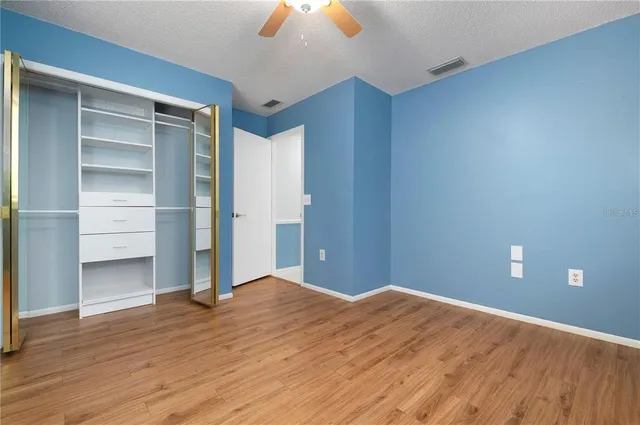 a view of empty room with wooden floor and fan