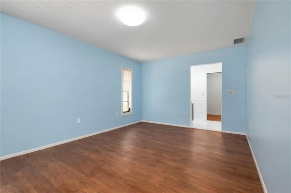 a view of an empty room with window and wooden floor