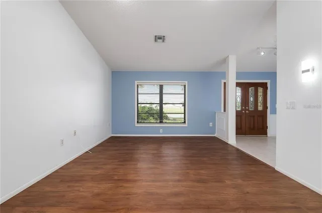 a view of an empty room with window and wooden floor