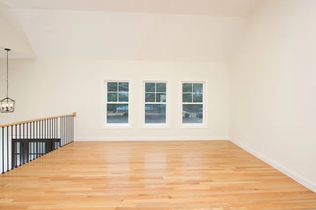 a view of an empty room with wooden floor and windows