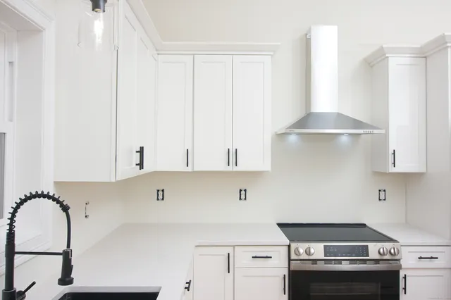 a kitchen with stainless steel appliances granite countertop a stove a sink and a white cabinets