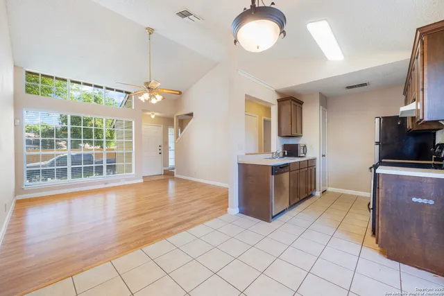 a kitchen with stainless steel appliances granite countertop a stove top oven a sink dishwasher a refrigerator and a fireplace with wooden floor