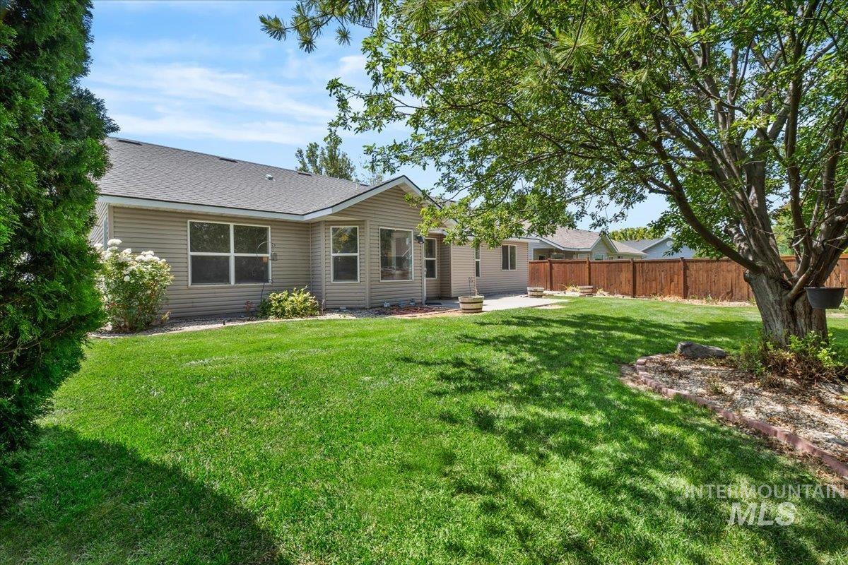 2032 Talus Loop Twin Falls, ID 83301 - Photo 42 of 43 Expansive backyard featuring a large tree, manicured lawn, and a wood fence