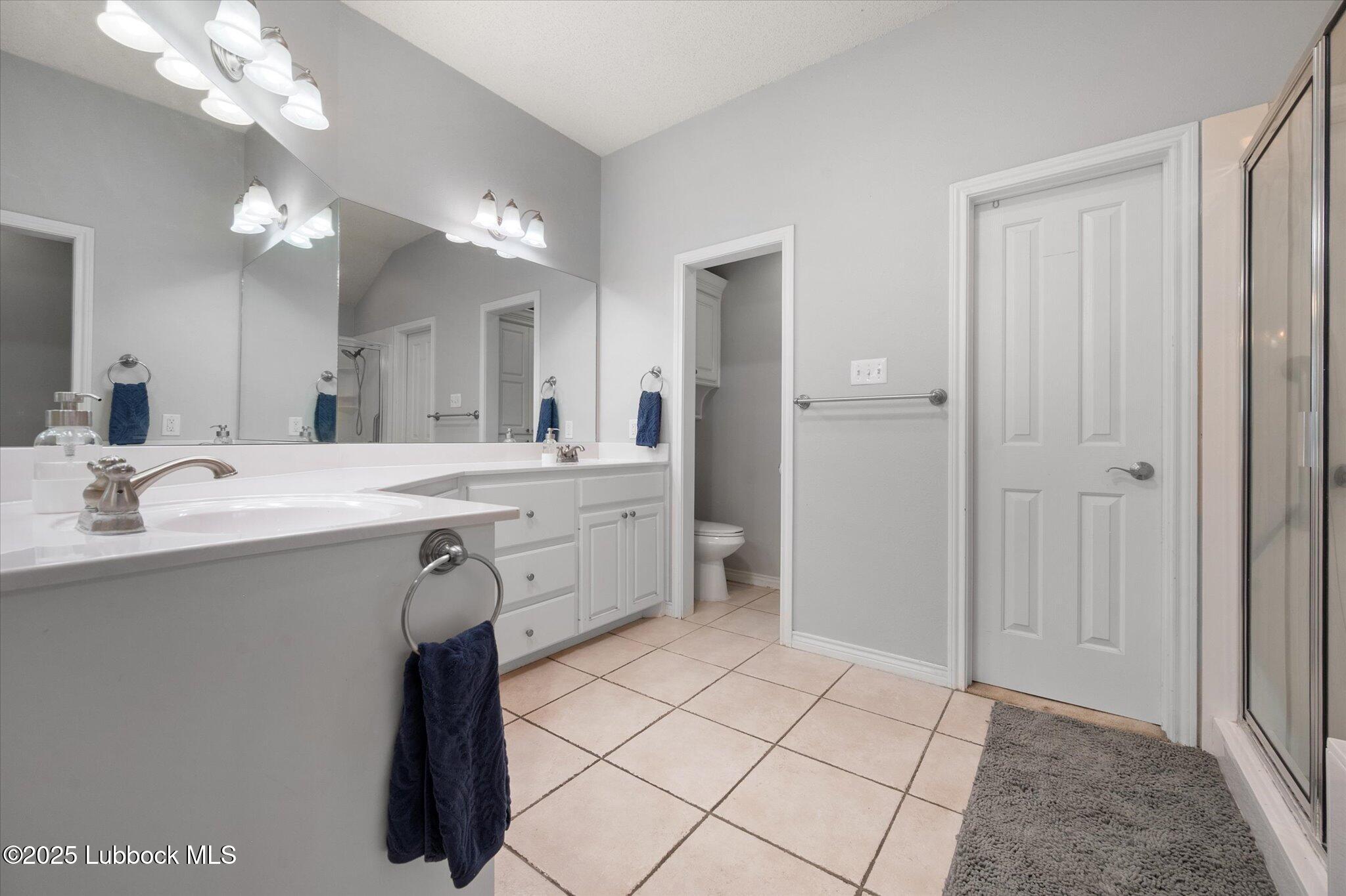 10401 Elgin Avenue Lubbock, TX 79423 - Photo 19 of 27 a bathroom with a sink a mirror and a shower