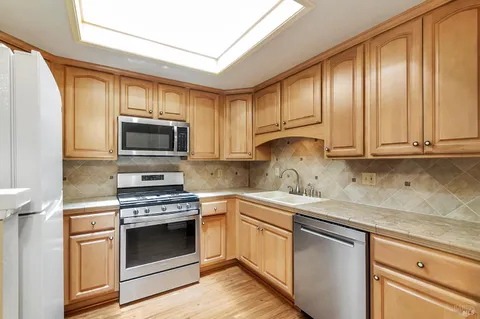 a kitchen with stainless steel appliances granite countertop a sink a stove and microwave