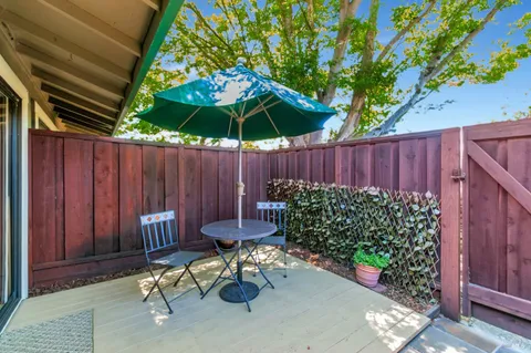 a view of a chairs and table under an umbrella in backyard