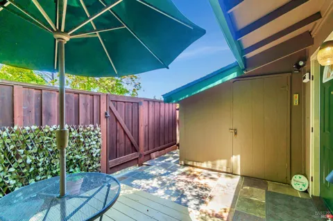 a backyard of a house with table and chairs under an umbrella