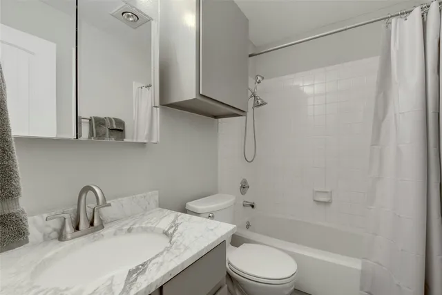 a bathroom with a granite countertop sink toilet and shower