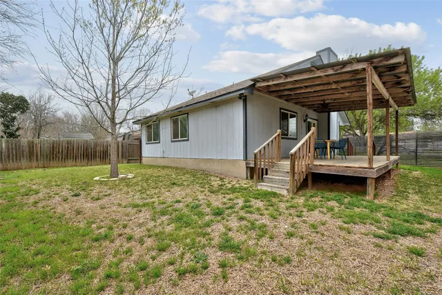 a backyard of a house with wooden stairs and table and chairs