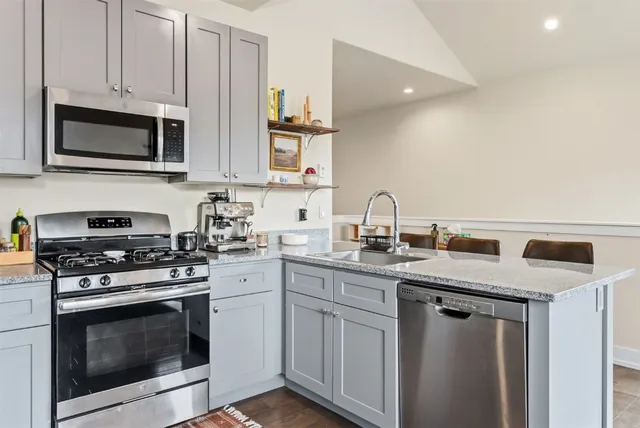 a kitchen with stainless steel appliances granite countertop white cabinets a stove a sink and dishwasher