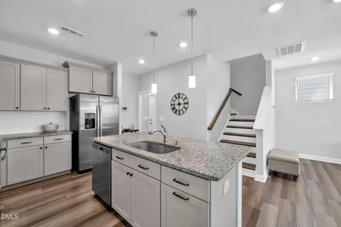 a kitchen with granite countertop a sink a counter space stainless steel appliances and cabinets