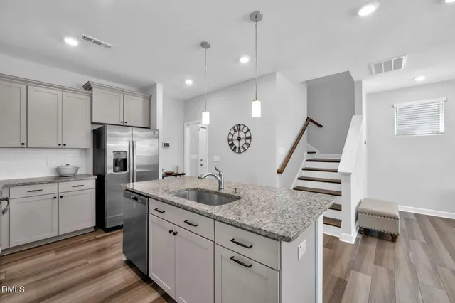 a kitchen with granite countertop a sink a counter space stainless steel appliances and cabinets