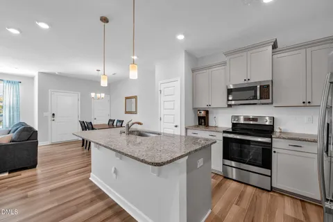 a kitchen with stainless steel appliances granite countertop a sink a stove and a wooden floors
