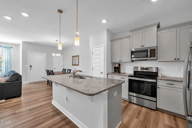 a kitchen with stainless steel appliances granite countertop a sink a stove and a wooden floors