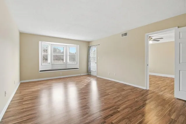a view of empty room with wooden floor and fan