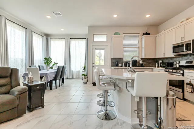 a living room with furniture a large window and dining table