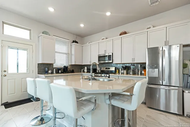 a kitchen with refrigerator a stove a dining table and chairs