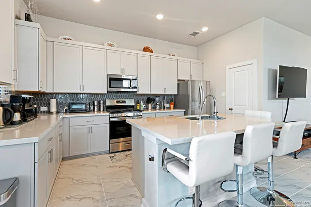 a kitchen with kitchen island granite countertop a sink counter top space appliances and cabinets