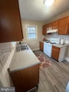 a kitchen with stainless steel appliances granite countertop a sink a stove top oven a chimney and a counter top space