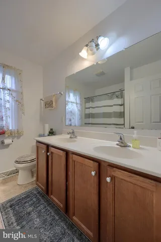 a bathroom with a granite countertop sink a toilet and a large mirror