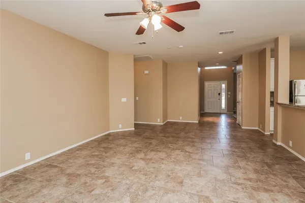 a view of an empty room and window with a kitchen