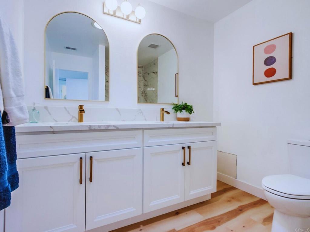 1025 Plover Way Oceanside, CA 92057 - Photo 17 of 36 a bathroom with a granite countertop sink a toilet and mirror