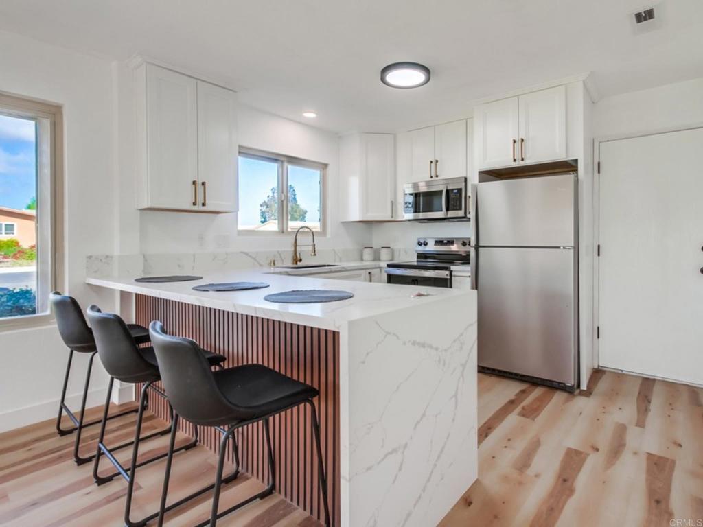1025 Plover Way Oceanside, CA 92057 - Photo 8 of 36 a kitchen with a refrigerator a stove a sink and a dining table with wooden floor