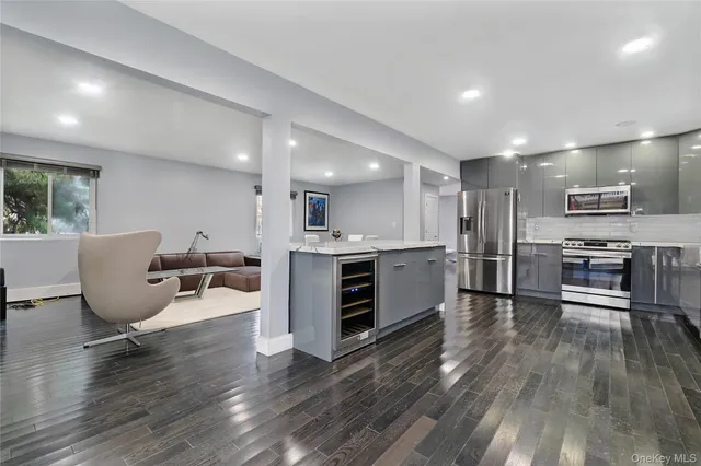 a living room with stainless steel appliances furniture and a kitchen view