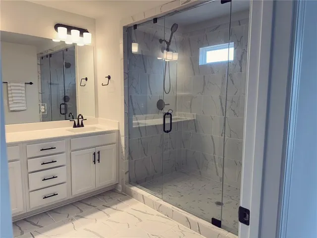 a bathroom with a shower sink and mirror