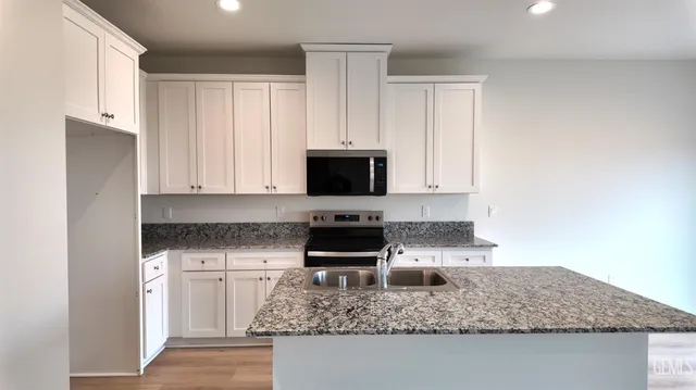 a kitchen with granite countertop white cabinets and stainless steel appliances