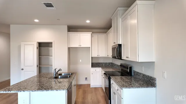 a kitchen with granite countertop kitchen island stainless steel appliances a sink stove and refrigerator
