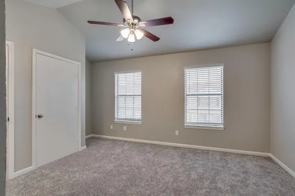 an empty room with chandelier fan and windows