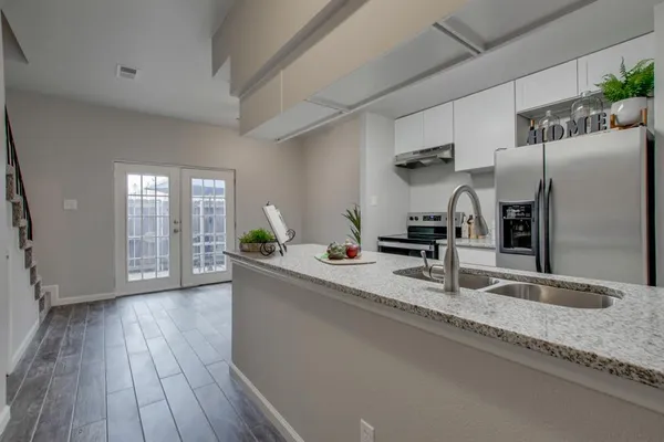 a kitchen with stainless steel appliances granite countertop a sink window and wooden floor