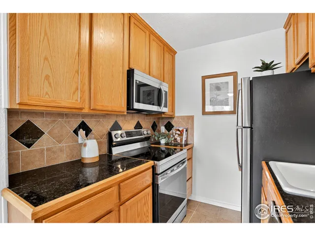 a kitchen with granite countertop a stove a sink and a microwave with cabinets