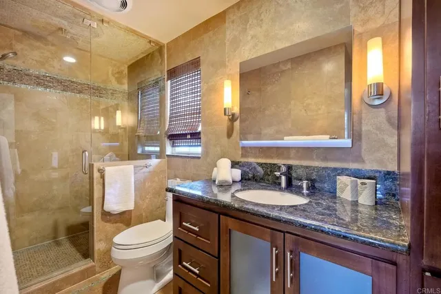 a bathroom with a granite countertop sink toilet and shower